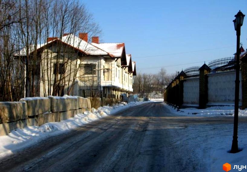 Зовнішній вигляд котеджного містечка КМ Сокольники з засніженими дахами. Прибудинкова територія з доріжками та огорожею.