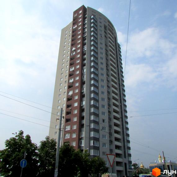 Висотна новобудова на вулиці Героїв полку «Азов» (Маршала Малиновського), 8, з сірими та коричневими фасадами, великою кількістю балконів та вікон. Навколо будівлі видно дерева та елементи міської інфраструктури.