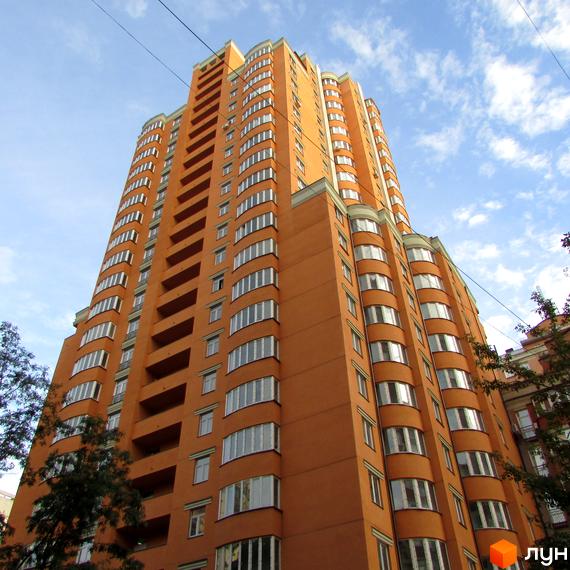 Вид на висотний будинок житлового комплексу Златоуст з балконами. Прибудинкова територія озеленена деревами.