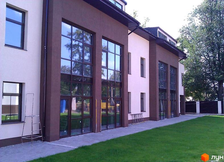 Зовнішній вигляд Таунхаус 'Холодногірський' з великими вікнами та прибудинковою територією з зеленим газоном.