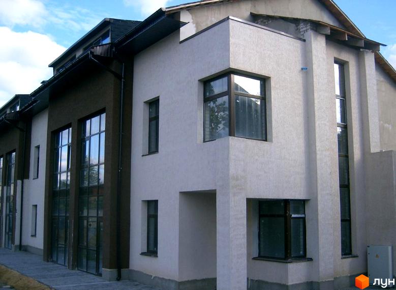 Зображення фасаду таунхаусу „Холодногірський“ з великими вікнами та світлим оздобленням. На передньому плані – доглянута прибудинкова територія.