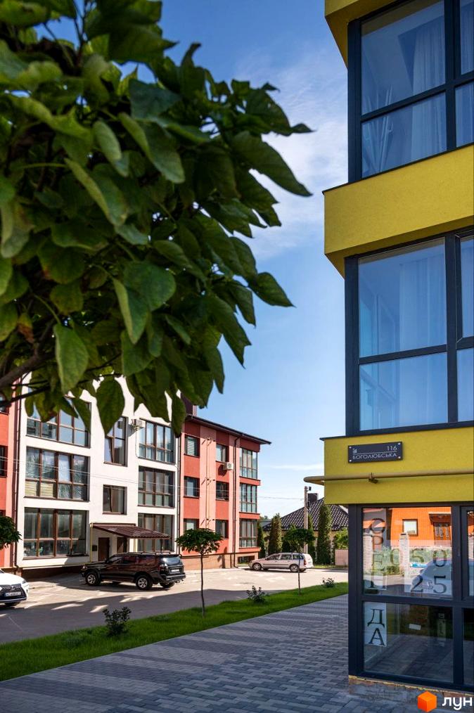 Житловий комплекс Італійський: фасади будівель з панорамними вікнами та прибудинкова територія з деревами та автомобілями.