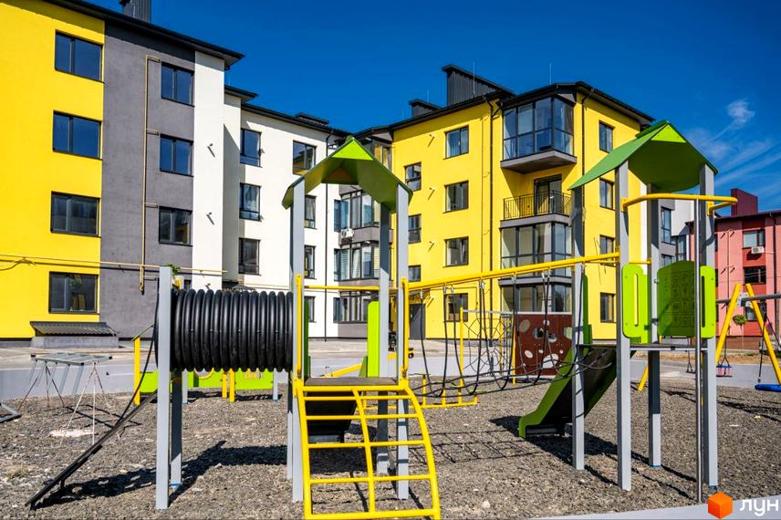 Житловий комплекс Італійський: яскраві фасади будинків та сучасний дитячий майданчик з гіркою та гойдалками.