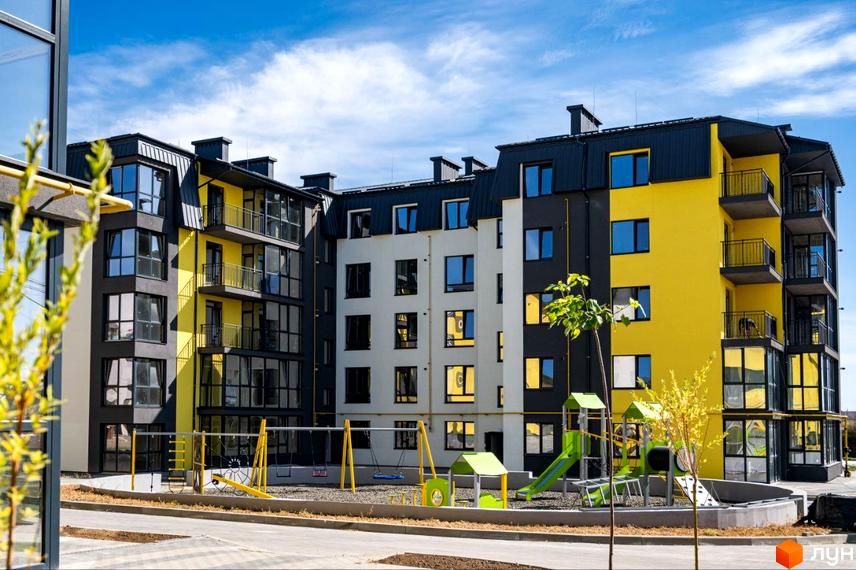Житловий комплекс Італійський - фасади будівель з жовтими та сірими елементами, балконами та дитячим майданчиком на території.
