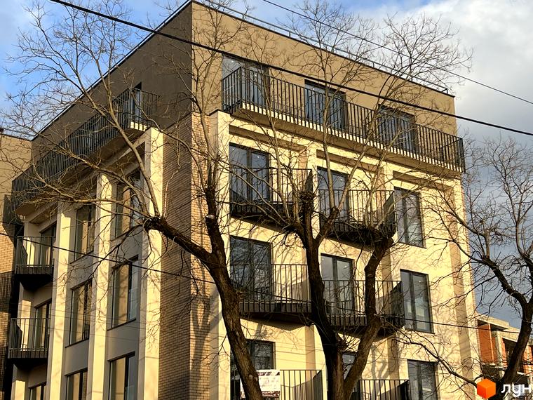 Житловий комплекс Родовід. Фасад будинку з балконами та вікнами, оточений деревами.