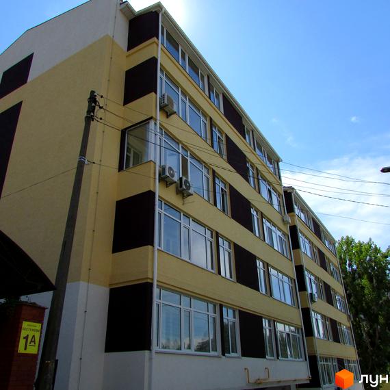 Житловий комплекс на Бестужева, 1А – фасадна частина новобудови з кондиціонерами та великими вікнами на тлі блакитного неба. Зовнішній вигляд будинку та прибудинкова територія.