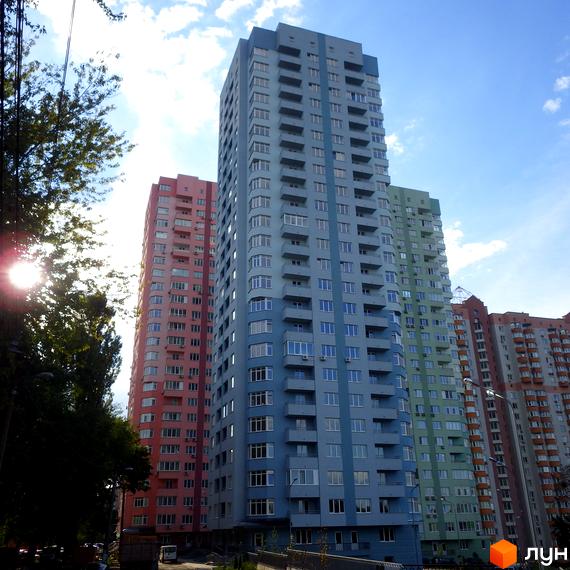 Багатоповерхові будинки житлового комплексу на вул. Феодосійська, 2. Видно блакитний, рожевий та зелений корпуси з балконами, а також прибудинкову територію.