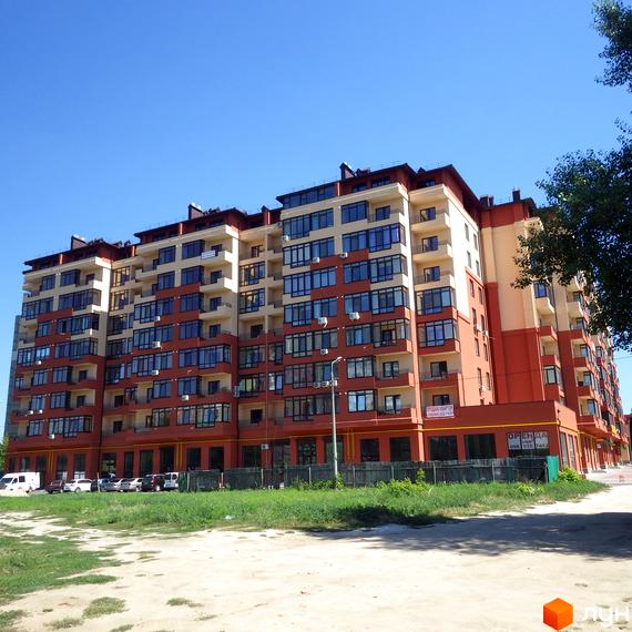 Зображення фасаду багатоповерхового будинку в Житловому комплексі Академмістечко. Вигляд новобудови та прибудинкової території в сонячний день.