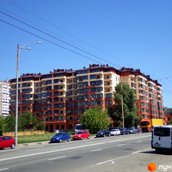 Зображення фасаду багатоповерхового будинку Житлового комплексу Академмістечко. На передньому плані дорога з автомобілями.