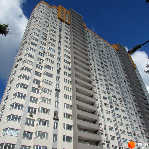 Фото фасаду багатоповерхового будинку в Житловому комплексі Лідер. Вигляд з низу вгору на висотну новобудову з великою кількістю вікон.