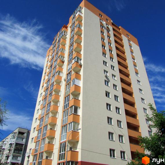 Зображення багатоповерхового будинку в Житловому комплексі Мінський. Вигляд фасаду будівлі та вікон з вулиці на тлі блакитного неба.