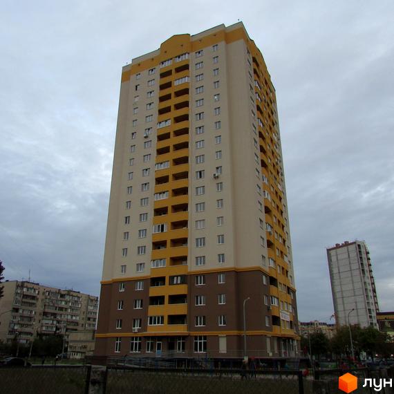Високоповерховий житловий комплекс на вул. Булгакова, 13. Будинок має світло-бежевий фасад із жовтими елементами та коричневим цоколем. Поруч видно іншу новобудову та міську забудову.