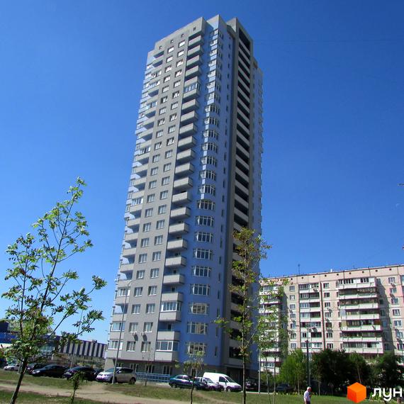 Висотна новобудова на вулиці Гмирі, 17, з сіро-блакитним фасадом та численними балконами. Навколо будинку зелена зона з деревами та припаркованими автомобілями.