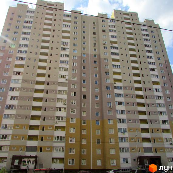 Житловий комплекс Милославичі, фасад будинку з балконами та вікнами. Прибудинкова територія з зеленими насадженнями.