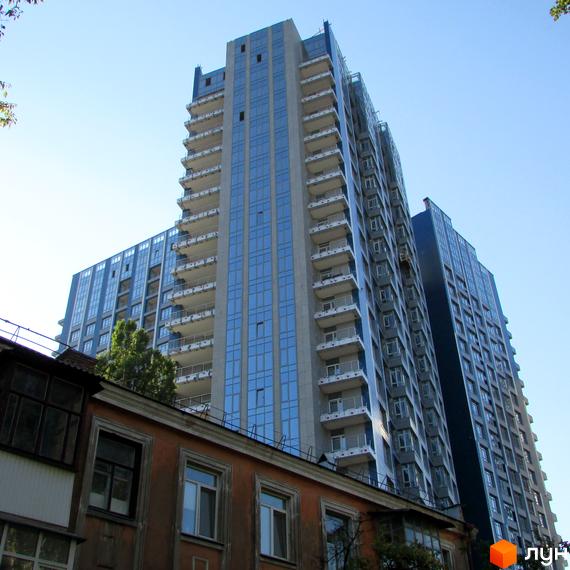 Житловий комплекс Central Park - висотні будинки з панорамним склінням та балконами на тлі блакитного неба. На передньому плані видно частину старої будівлі.