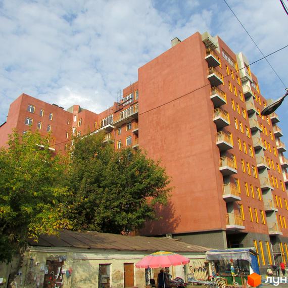 Зображення фасаду Житлового комплексу Brooklyn з балконами. Вигляд на частину прибудинкової території з деревами та торговими рядами.