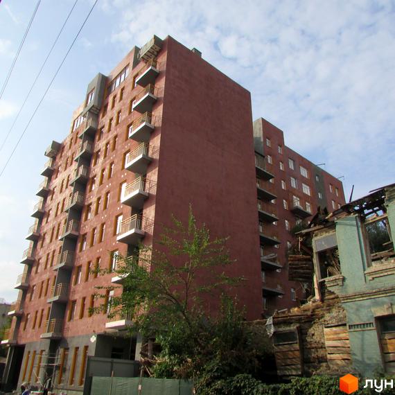 Зображення фасаду багатоповерхового будинку в ЖК Бруклін. Вигляд новобудови з балконами та прилеглою територією.