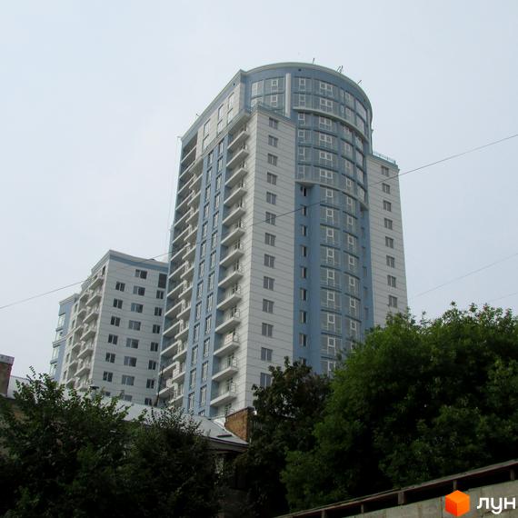 Житловий комплекс Срібна Вежа з висотними будинками та балконами. Прибудинкова територія з зеленими насадженнями.