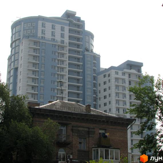 Житловий комплекс Срібна Вежа з сучасною архітектурою на фоні старої будівлі. Приблизно зелені насадження навколо.