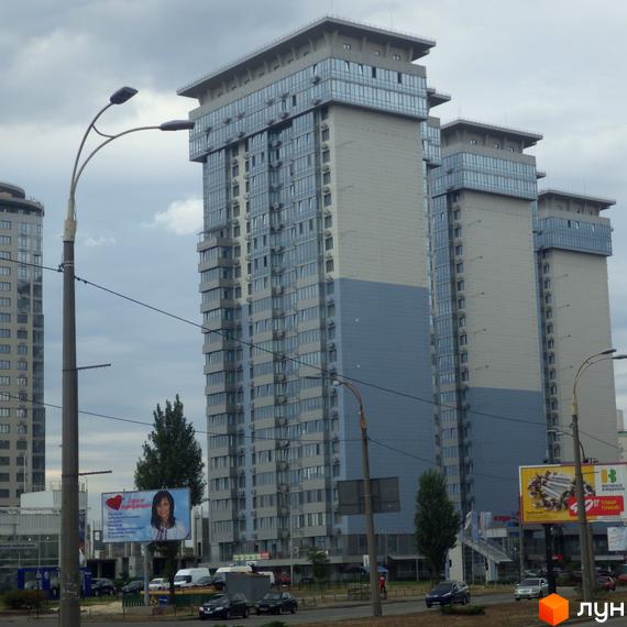 Житловий комплекс RiverStone - три висотні будинки з панорамним склінням та сірими фасадами. Навколо зелені насадження та міська інфраструктура.