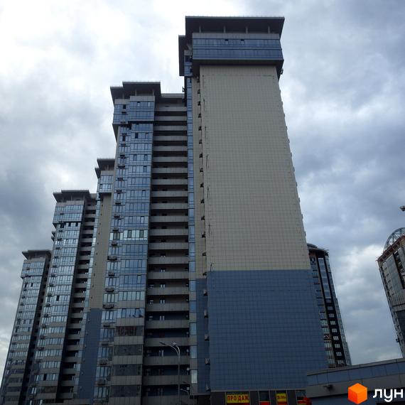 Вид на висотні будинки житлового комплексу RiverStone з фасадами зі скла та бежевої плитки. Будинки мають багато балконів та сучасну архітектуру.