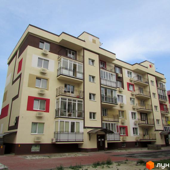 Житловий комплекс Голосіївський квартал: багатоповерховий будинок з бежевим фасадом, коричневими та червоними акцентами, балконами. Видно прибудинкову територію.