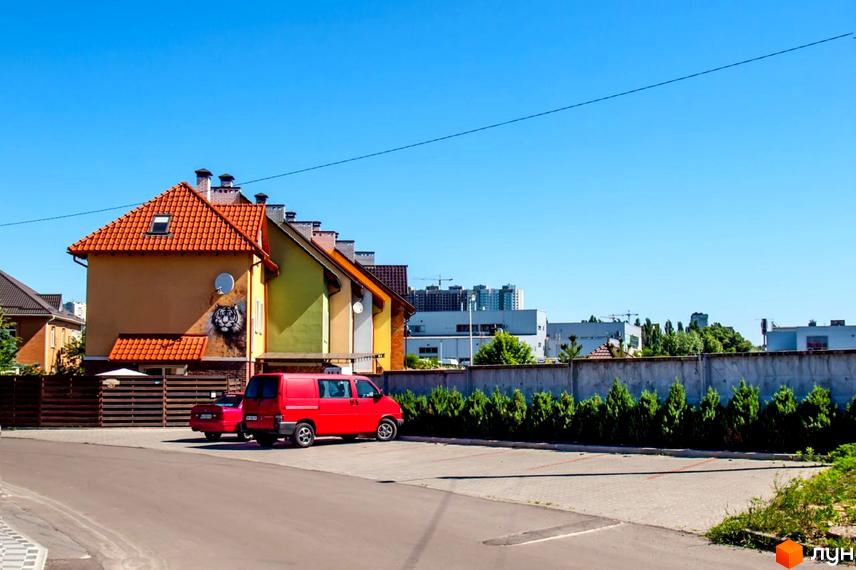 Цегляний будинок з помаранчевою черепицею на даху. На фасаді зображено тигра. Поруч припарковані автомобілі, а також є зелені насадження.