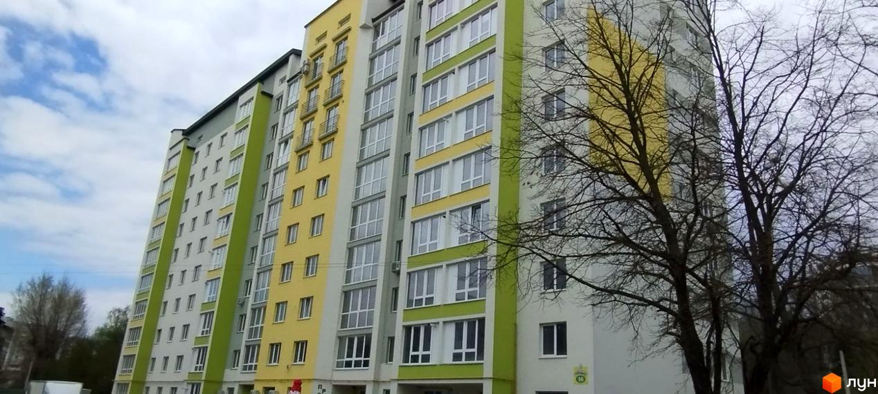 Багатоповерховий будинок ЖК Галичина з великими вікнами та балконами. Зелені смуги на фасаді додають яскравості, а дерева перед будинком створюють атмосферу.