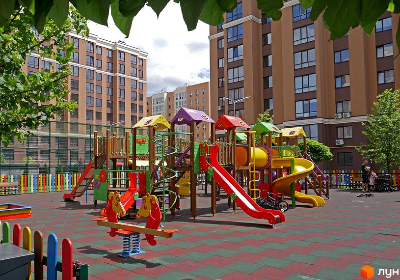 Житловий комплекс Софіївські Липки: дитячий майданчик з гірками та гойдалками на фоні багатоповерхових будинків.
