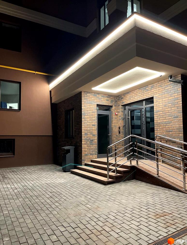 Зовнішній вигляд новобудови ЖК Софіївські Липки з цегляним фасадом та підсвіткою. Прибудинкова територія вимощена плиткою з пандусом та сходами.