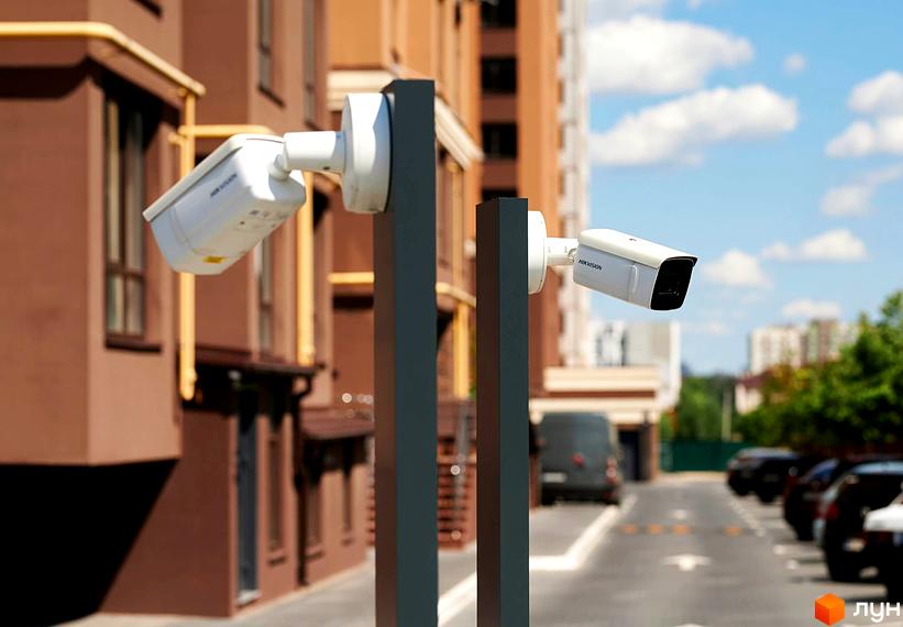 Зовнішній вигляд будинку ЖК Софіївські Липки з камерами відеоспостереження та парковкою автомобілів.