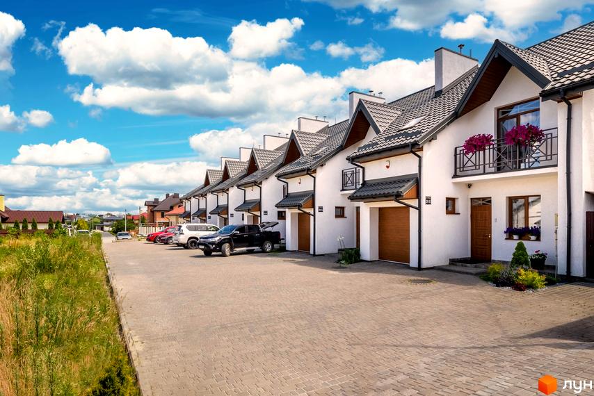 Житловий комплекс на вул. Леся Курбаса, 6: ряд білих котеджів з темними дахами та парковка.