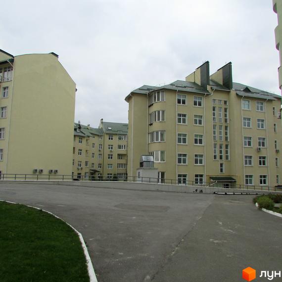 Житловий комплекс Петропавлівський: світлі будинки з багатьма вікнами та зеленими дахами, прибудинкова територія з асфальтованою дорогою.