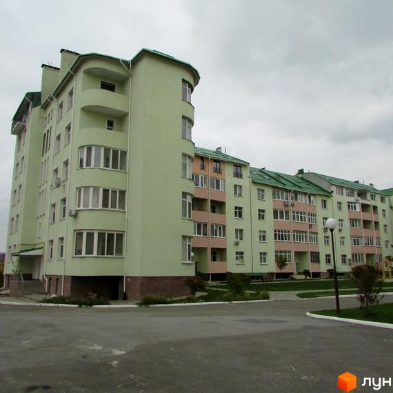 Житловий комплекс Петропавлівський: світло-зелені будинки з зеленими дахами та балконами персикового кольору. На передньому плані асфальтований проїзд та зелені насадження.