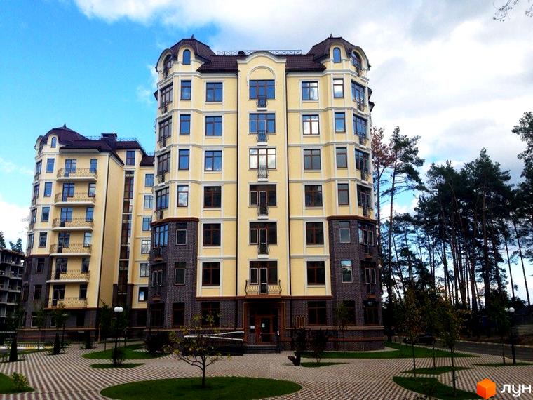 Житловий комплекс Rich Town. Багатоповерховий будинок з жовтим фасадом та темними елементами. На території комплексу бруківка, газон та дерева.