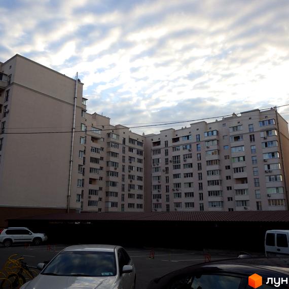 Житловий комплекс Софіївський з сучасними фасадами. Прибудинкова територія з автомобілями та облаштованими місцями для паркування.