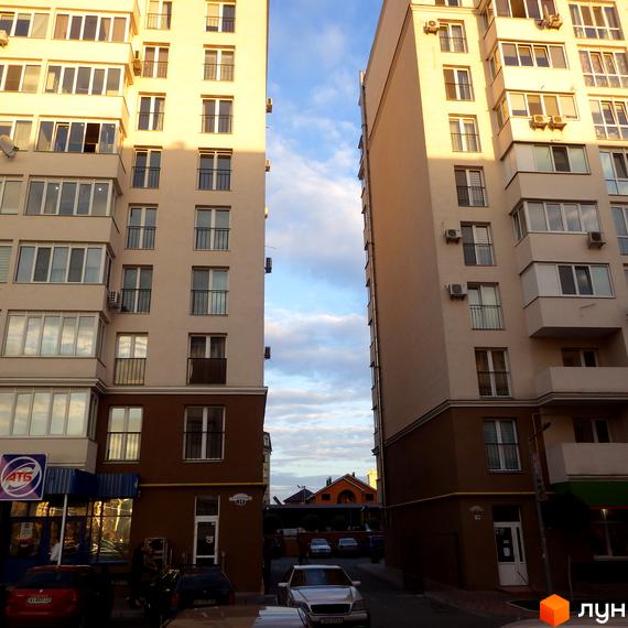 Житловий комплекс Софіївський з двома багатоповерхівками та прибудинковою територією з автомобілями та магазинами.