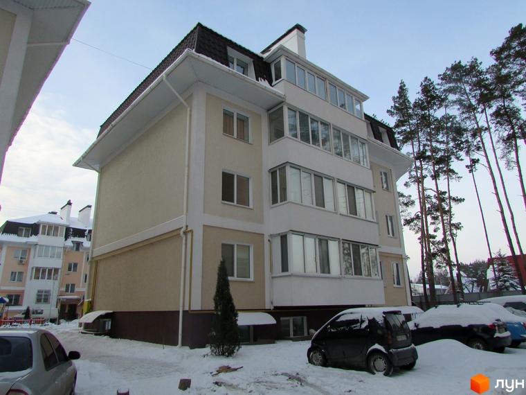 Зовнішній вигляд житлового комплексу ЖК Матросова з фасадом світло-бежевого кольору та білими елементами. На прибудинковій території видно засніжену землю та припарковані автомобілі.