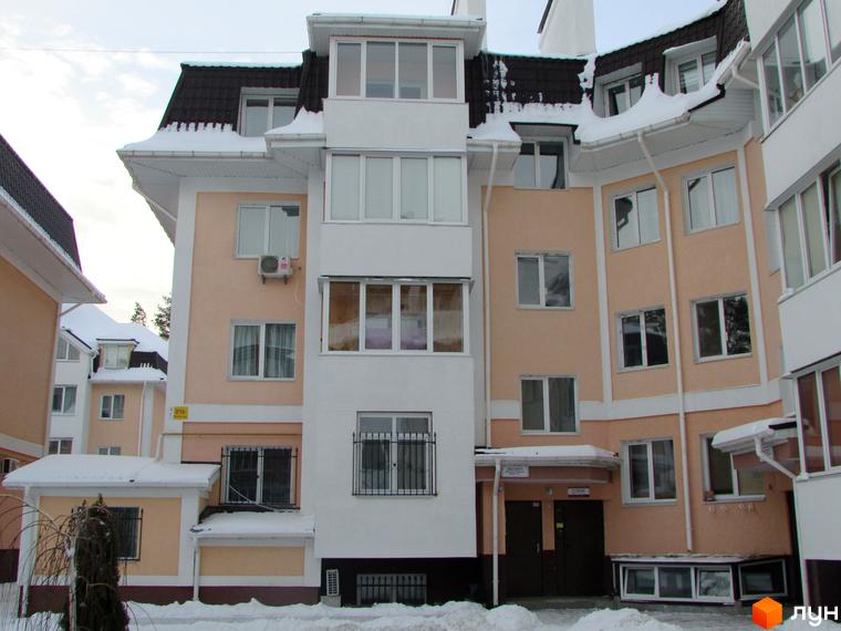 Зовнішній вигляд житлового комплексу ЖК Матросова, що складається з кількох секцій з білими та персиковими фасадами, покритих снігом дахів. Навколо будинку видно засніжену територію.