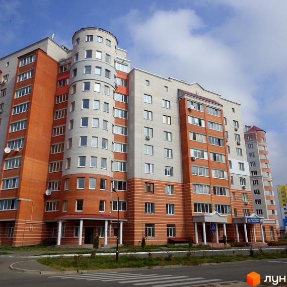 Зовнішній вигляд житлового комплексу ЖК Городок з червоною та сірою фасадною обробкою. Прибудинкова територія з зеленими насадженнями та пішохідними доріжками.