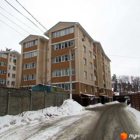 Житловий комплекс Квартал на „Київській“ з фасадом у світлих тонах та прибудинковою територією, засніженою взимку.