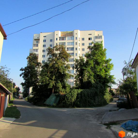 Багатоповерховий житловий будинок на вул. Нова, 4, білого кольору з вікнами та балконами. Оточений зеленими деревами та чагарниками, з дорогою на передньому плані.