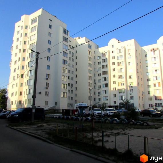 Житловий комплекс на вул. Нова, 4, з сучасним фасадом та прибудинковою територією, де розташовані автомобілі та дитячий майданчик.