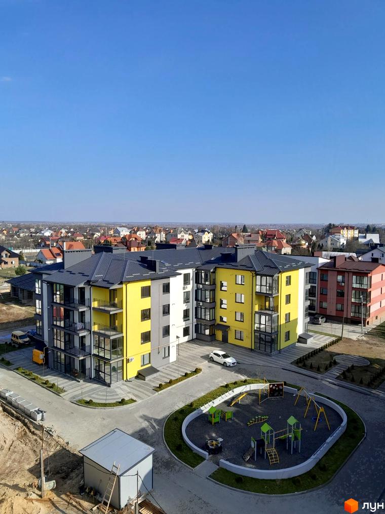 Житловий комплекс Італійський: фасади будівель в жовтих та сірих тонах, з балконами та великими вікнами. Поруч дитячий майданчик та парковка.