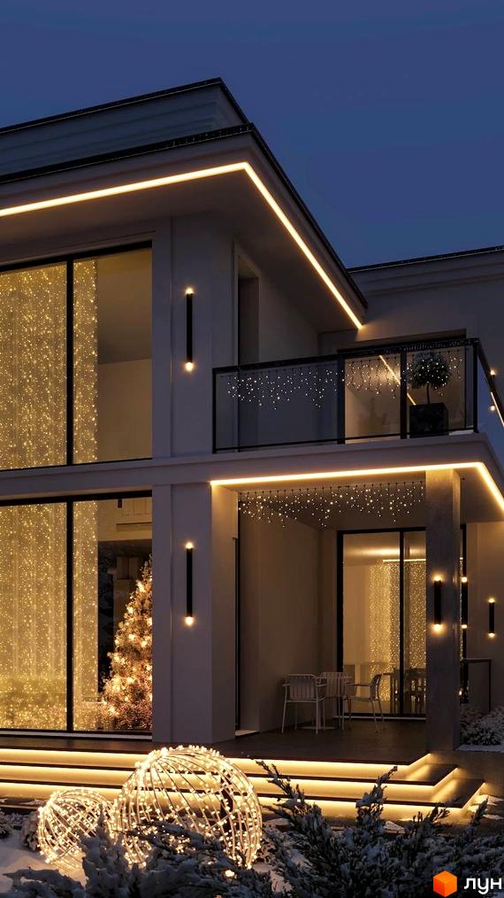 Котеджне містечко Затишна Солонка: двоповерховий будинок з підсвіченим фасадом та вікнами, прикрашений новорічними гірляндами та світловими кулями на снігу.