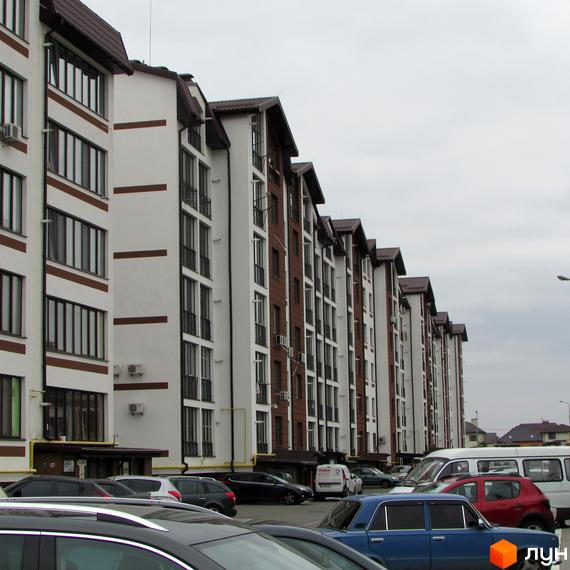 Житловий комплекс Празький квартал з біло-коричневими фасадами та парковкою перед будинками.