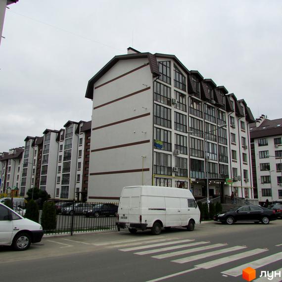 Житловий комплекс Празький квартал. Зовнішній вигляд багатоквартирних будинків з білими фасадами та коричневими елементами. Прибудинкова територія з парковкою та пішохідним переходом.