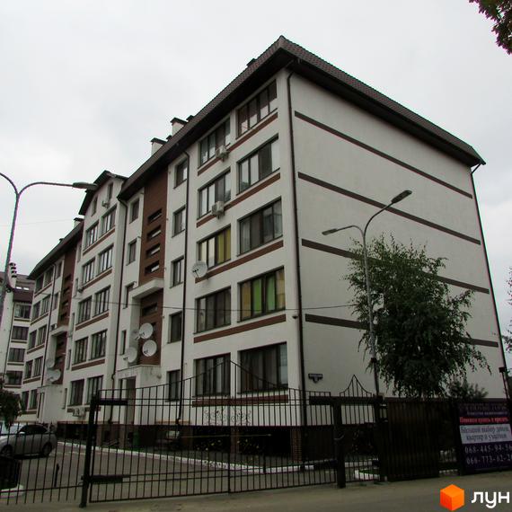 Житловий комплекс Празький квартал - багатоповерхові будинки з біло-коричневим фасадом та темним дахом. Прибудинкова територія огороджена парканом, є зелені насадження та вуличне освітлення.