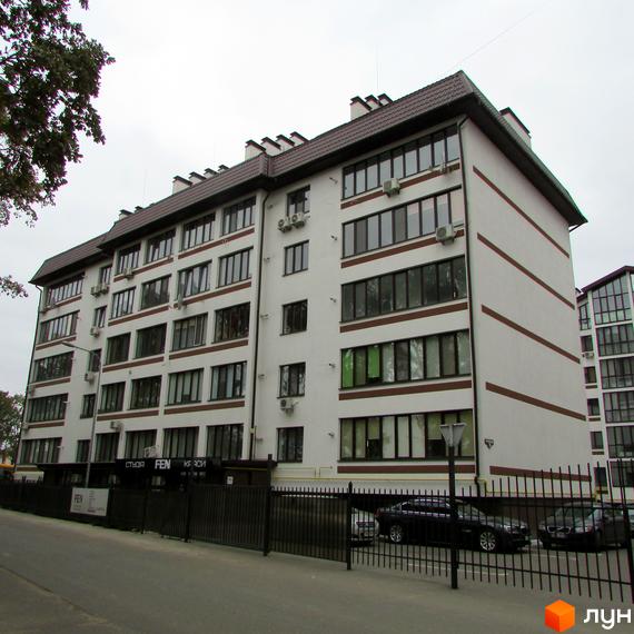 Житловий комплекс Празький квартал з білим фасадом та коричневими смугами, вікнами та кондиціонерами. Перед будинком паркан та припарковані автомобілі.