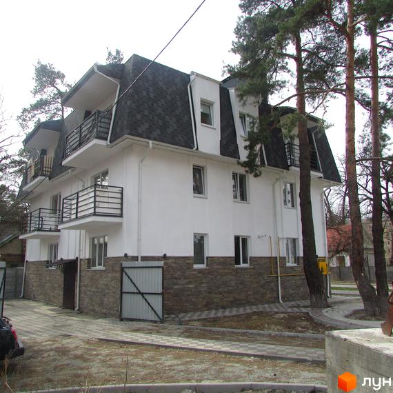 Клубний будинок „Полтавська, 80“ з білими стінами, темним дахом та балконами. Навколо будинку викладена бруківка та ростуть дерева.